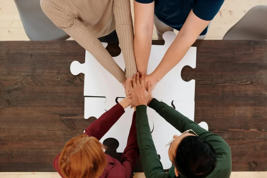 Image représentant des mains les unes sur les autres pour comprendre le coaching d'équipe avec des pièces de puzzles