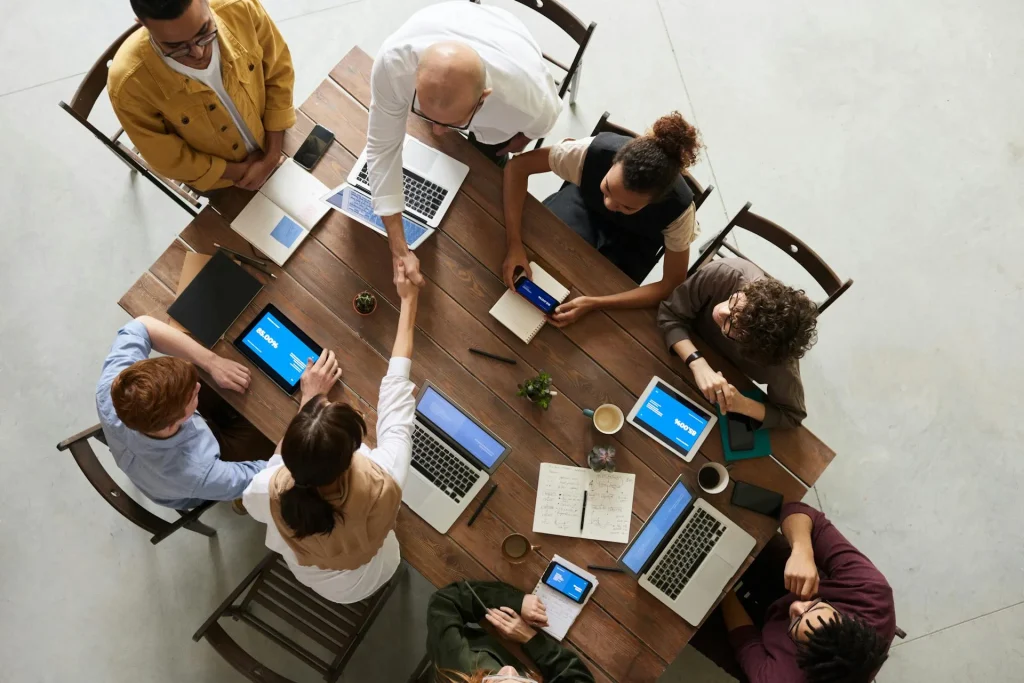 Image représentant vue d'en haut des personnes qui travaille ensemble avec des ordinateurs et des téléphones pour la page coaching managérial